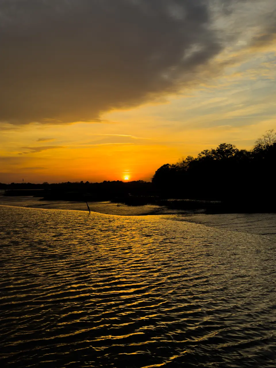 The sun setting over rippled water on the Ashley River in Charleston, SC