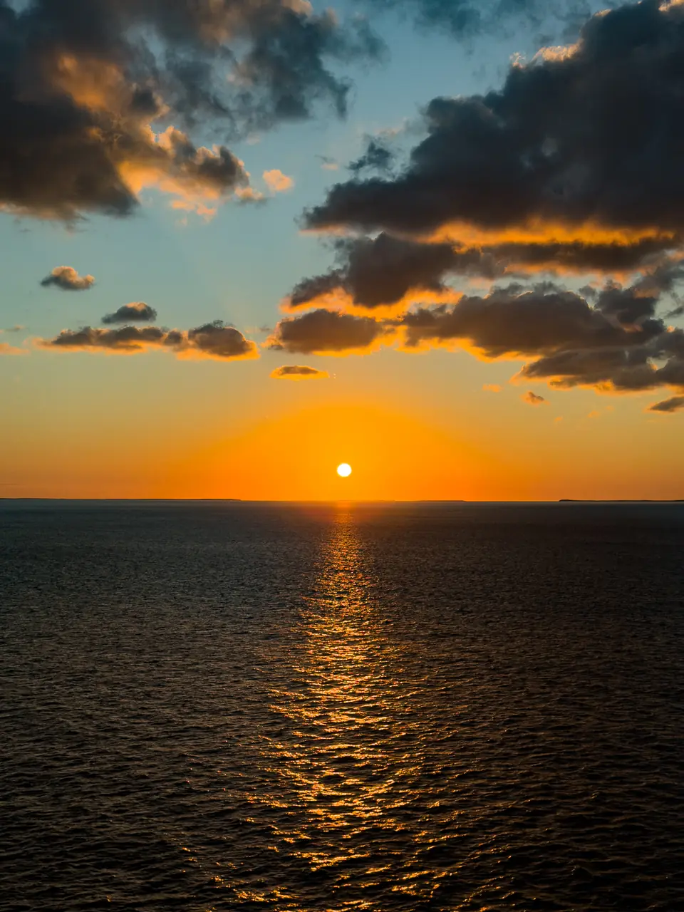 The sun setting over the open ocean with a golden path across the water