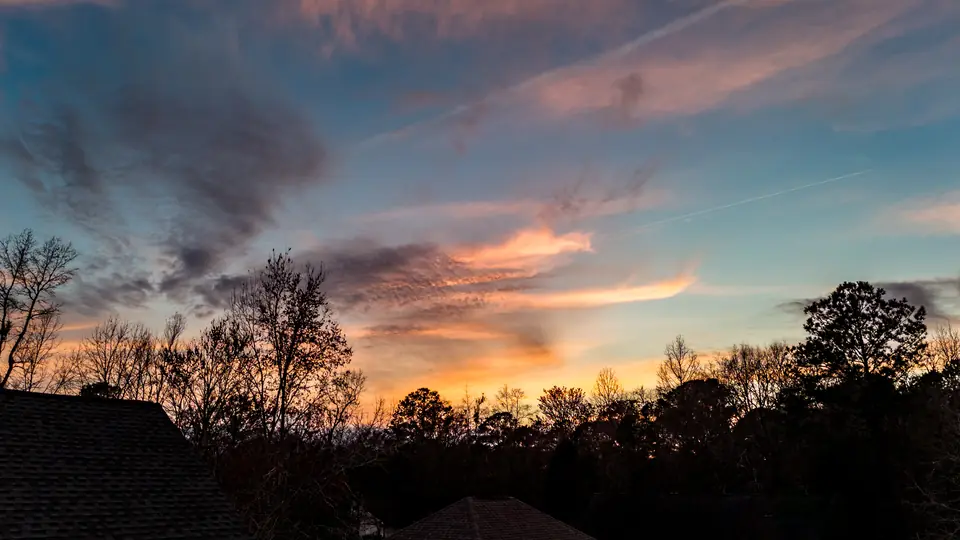 Pink and orange sunset clouds over bare winter trees in Moncks Corner, SC