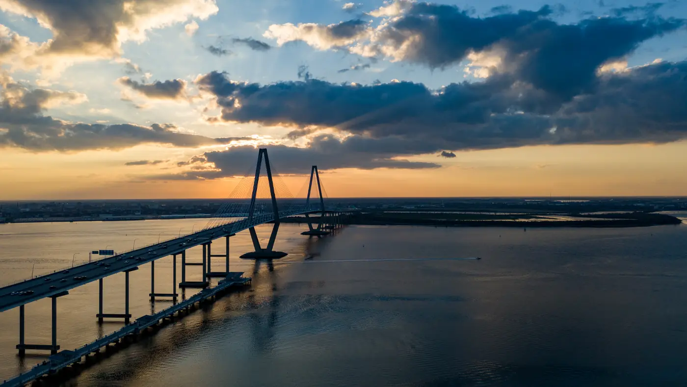 Drone view of the Ravenel Bridge over the Cooper River at golden hour with dramatic clouds